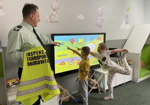 dzieci rozwiązują zagadki na monitorze interaktywnym